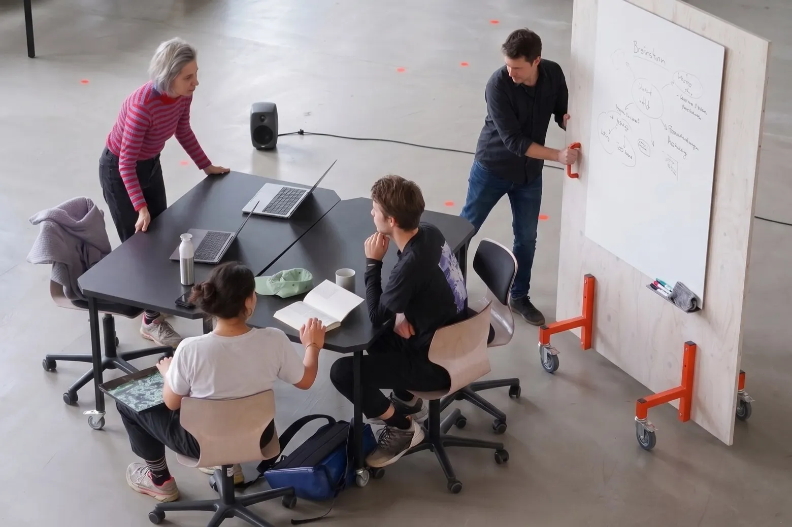 A group works around mobile tables and a wheeled whiteboard in the Co-Lab.