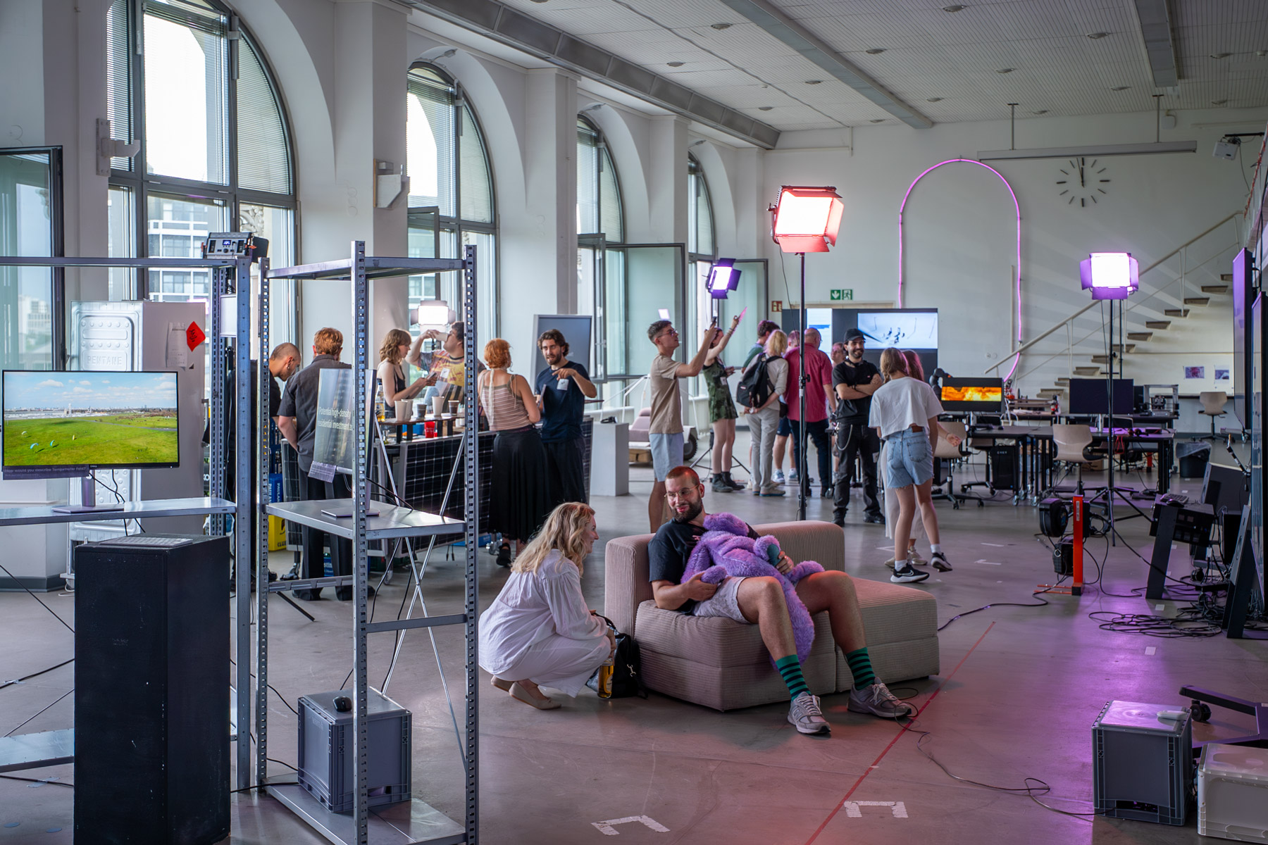 A public event in the Co-Lab, with visitors, installations, mobile furniture and presentation equipment distributed throughout the space.